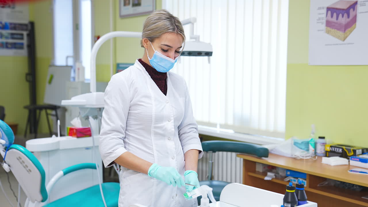 Female student of dentistry department preparing materials for practicing. Young lady using forceps to pick up details from a box.