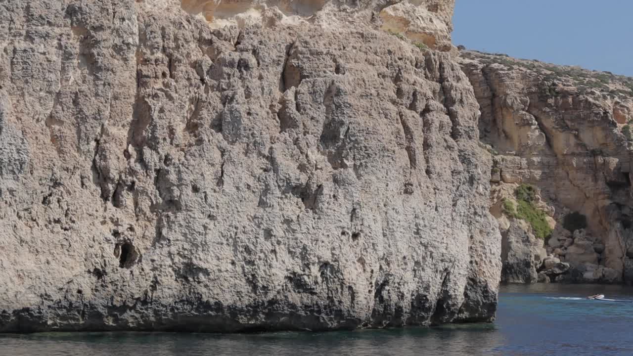 pasando cerca de la laguna de cristal en comino, malta, una bahía protegida enmarcada por altos acantilados de piedra caliza