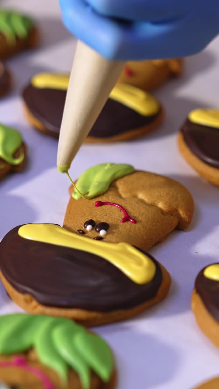 Cookies production in confectionary factory. Hands in gloves decorate biscuits in the shape of mushrooms with creamy decorations. Close up. Vertical video