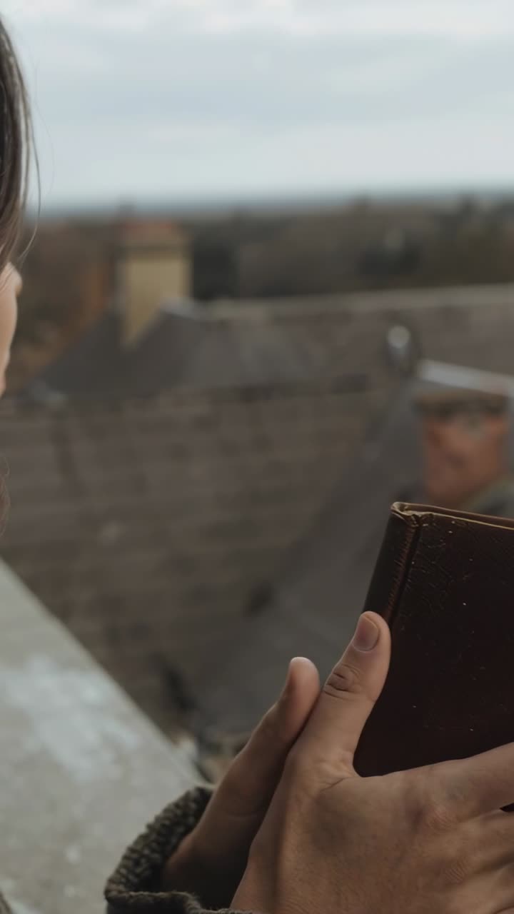Video verticale: Inquadratura di donna in maglione che alterna lo sguardo tra un libro e i tetti su una sporgenza, con spazio per il testo.