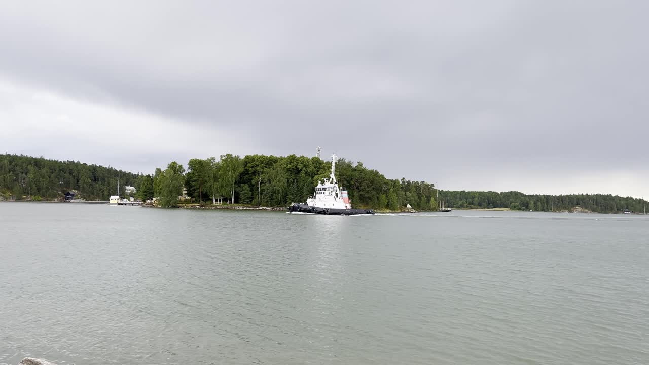 Tug boat passing by an island through narrow archipelago fairway