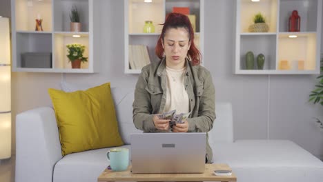 woman counting money at laptop.