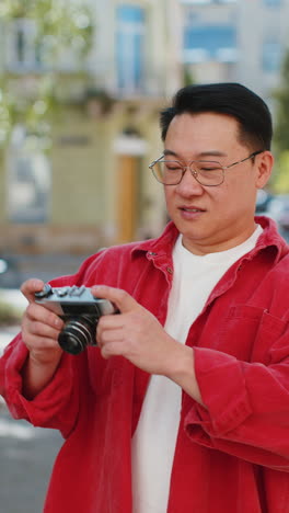 asian man tourist traveling on weekends exploring city making photo pictures on retro vintage camera