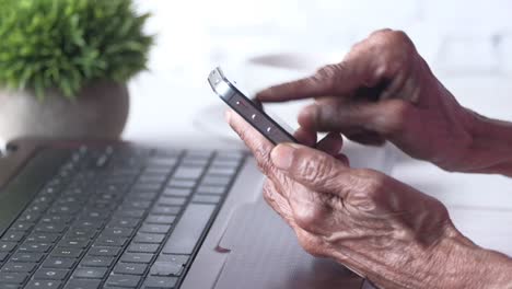 elderly person using a smartphone and laptop