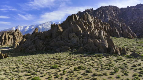 Drone-tilting-toward-rocky-cliffs,-sunny-day-in-Alabama-Hills,-California,-USA