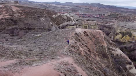 Luftaufnahmen-Von-Drohnen-Umkreisen-Eine-Frau-Beim-Wandern-Im-Rose-Valley,-Kappadokien,-Türkei