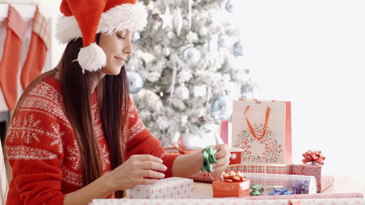 una mujer joven sentada envolviendo regalos de navidad.