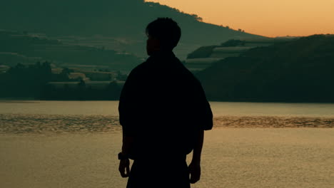 man silhouetted at sunset lake view