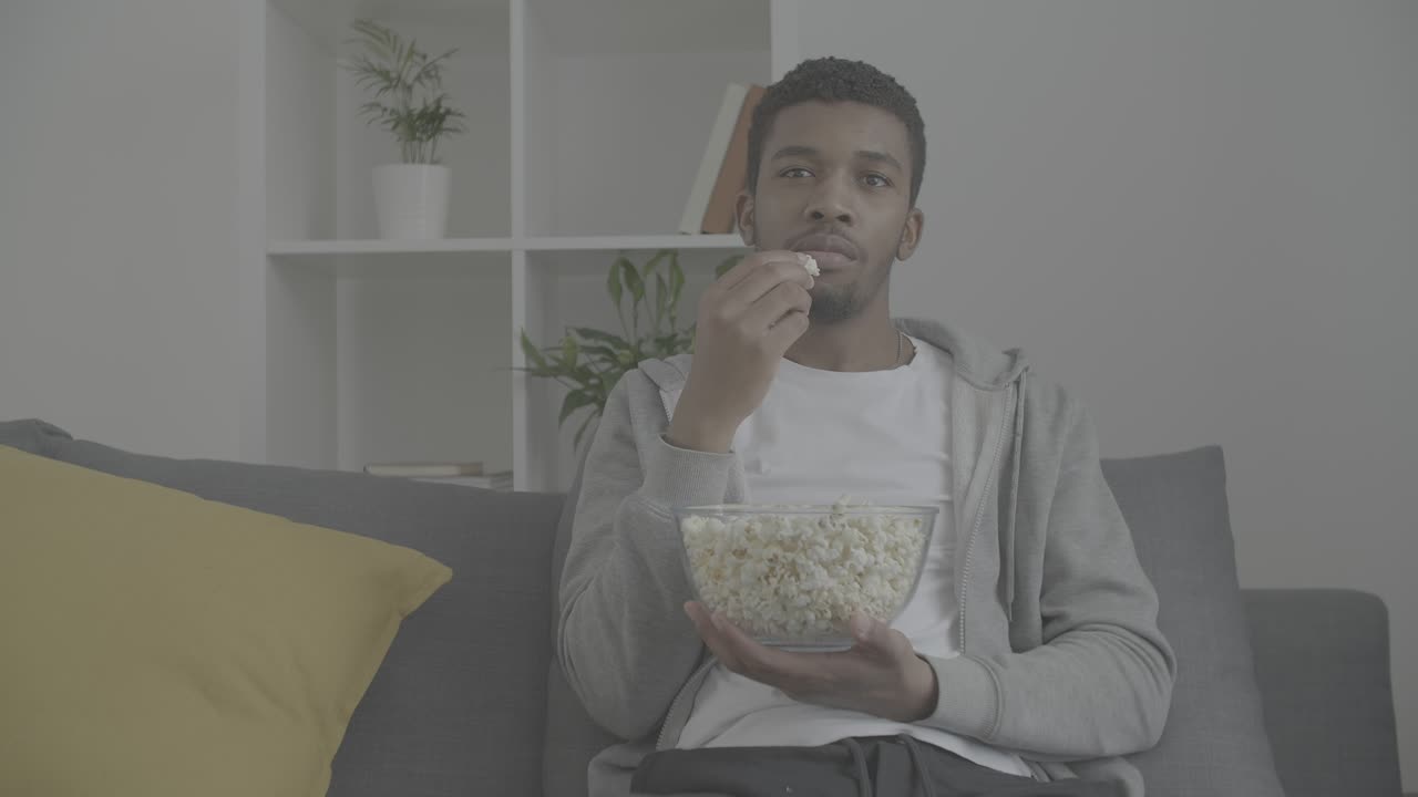 주의 깊게 영화를 보고 팝콘을 먹는 젊은 아프리카계 미국인 남성