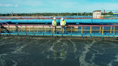 two wastewater operators observing a large sewage cleaning facility