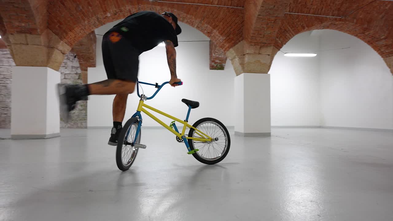 a man on a bike doing tricks indoors - smooth gimbal shot