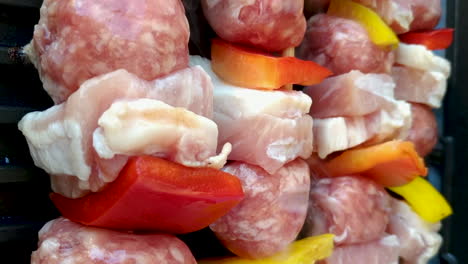 vista vertical de brochetas crudas a la parrilla, pollo, salchicha y pimienta, estática
