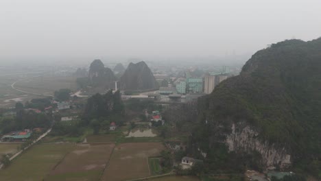 aerial misty drone shot of houses and factories behind the mountain