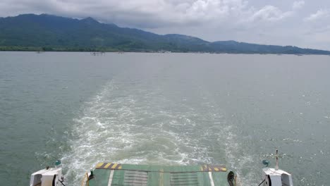 Blick-Auf-Die-Bergige-Küste-Vom-Heck-Eines-Davonsegelnden-Bootes,-Das-Kielwasser-über-Das-Meer-Hinterlässt