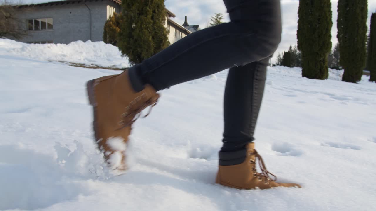 Mujer caminando por la nieve invernal con botas