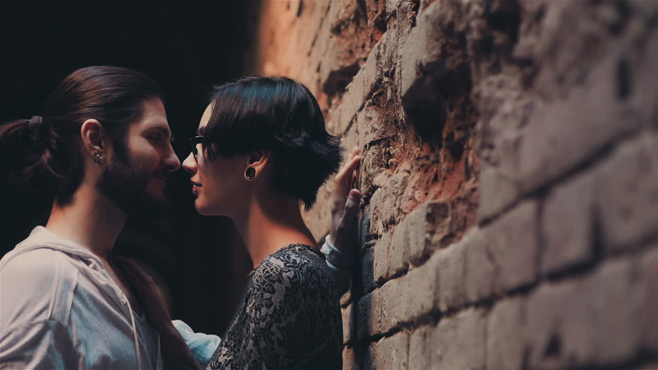 joven pareja hipster gótica admirándose unos a otros en el fondo de la pared de ladrillo