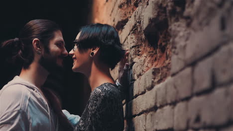 young gothic hipster couple admiring each other on the background of brick wall