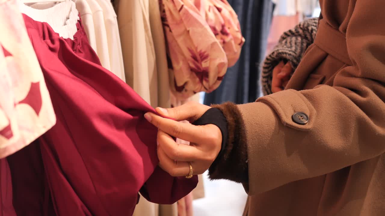 Close-up of Woman's Hand Touching Red Fabric in Clothing Store