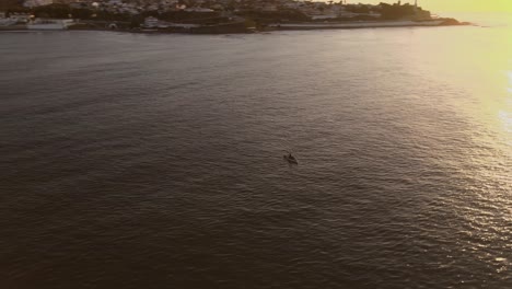 Aerial-Pan-Right-Shot-of-Colorful-Sunset-Reflected-on-Sea-Surface-with-Small-Boat