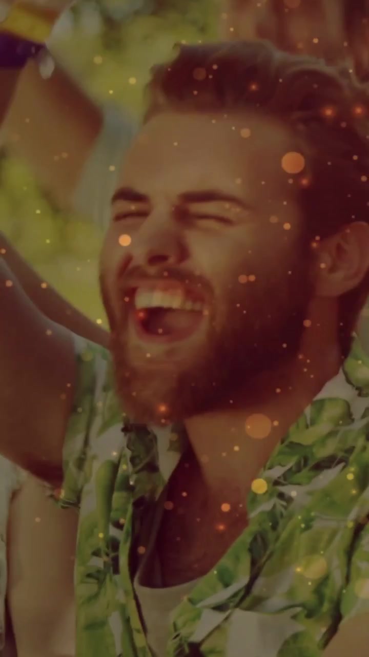 Dikey video: Sakallı adam müzik başladığında bağırıyor ve kollarını kaldırıyor, ışıltılı bokeh beliriyor.