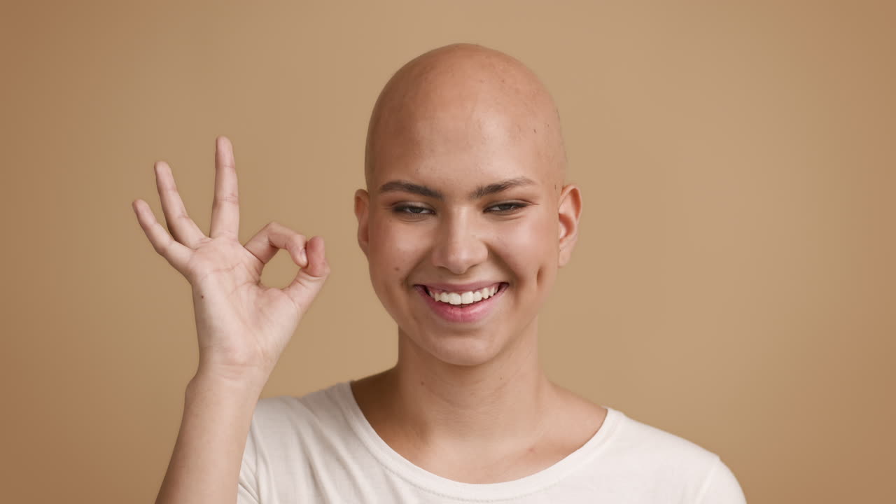 Smiling Woman with Bald Head Giving an OK Sign