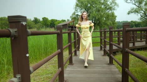 slender figure young woman in yellow dress modeling on wooden walkway