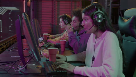 team of four cybersport gamers playing virtual video games while eating potato chips and drinking coffee