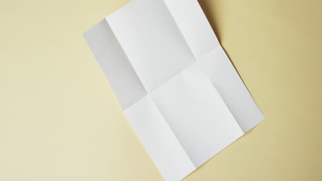 video of piece of white paper with creases on yellow background