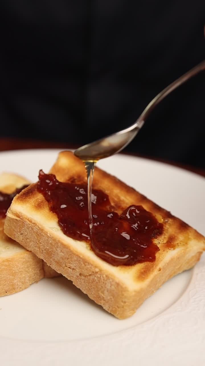 Pouring Golden Honey onto Sweet Jam and Toast