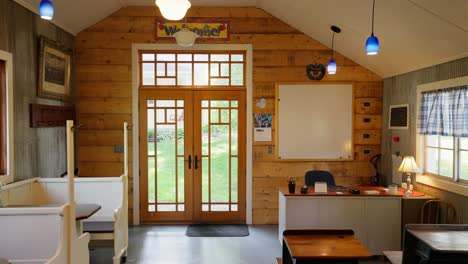 panning shot of the interior of a school house classroom showing the front door, whiteboard, and teacher's desk