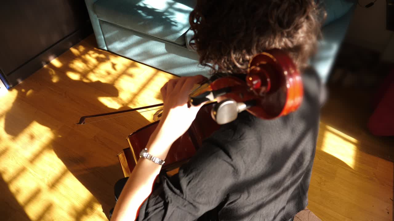 Fågelperspektiv av person som spelar cello i soligt rum
