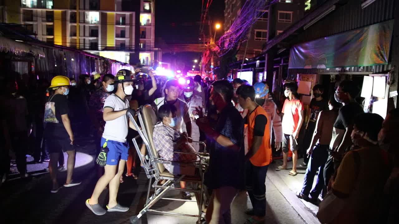 An Elderly Man Rescued by Medical and Fire Crew on Scene at a House Fire in Ratchada Soi 36, Bangkok, Thailand at Night from an Explosion in the Home.
