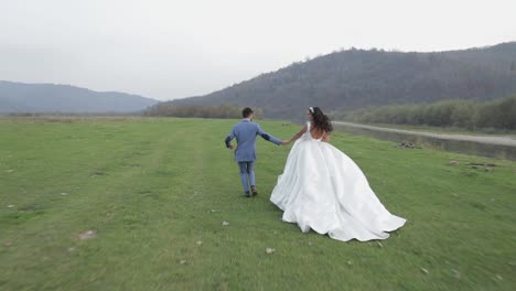 Wedding-couple-running-near-mountain-river.-Groom-and-bride-in-love