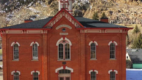 raising up drone shot of red church in utah with mountain and tree in the background