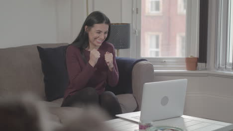 young attractive woman celebrates as her team scores and she wins online bet - ungraded