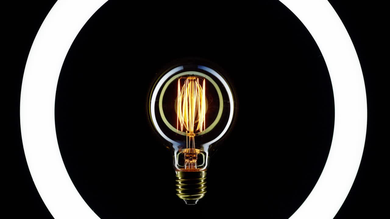 una bombilla de tungsteno parpadeando sobre un fondo negro.