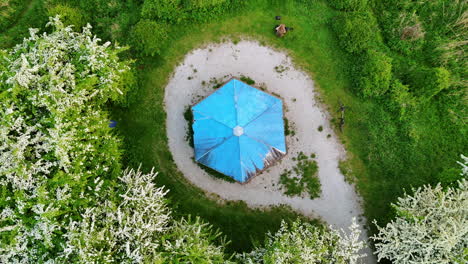 rising over the blue roof of gazebo in the green nature. blossoming trees grow around the lawn.