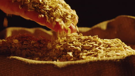 hand pouring oats into a burlap sack