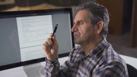 man examining document on computer. thoughtful.