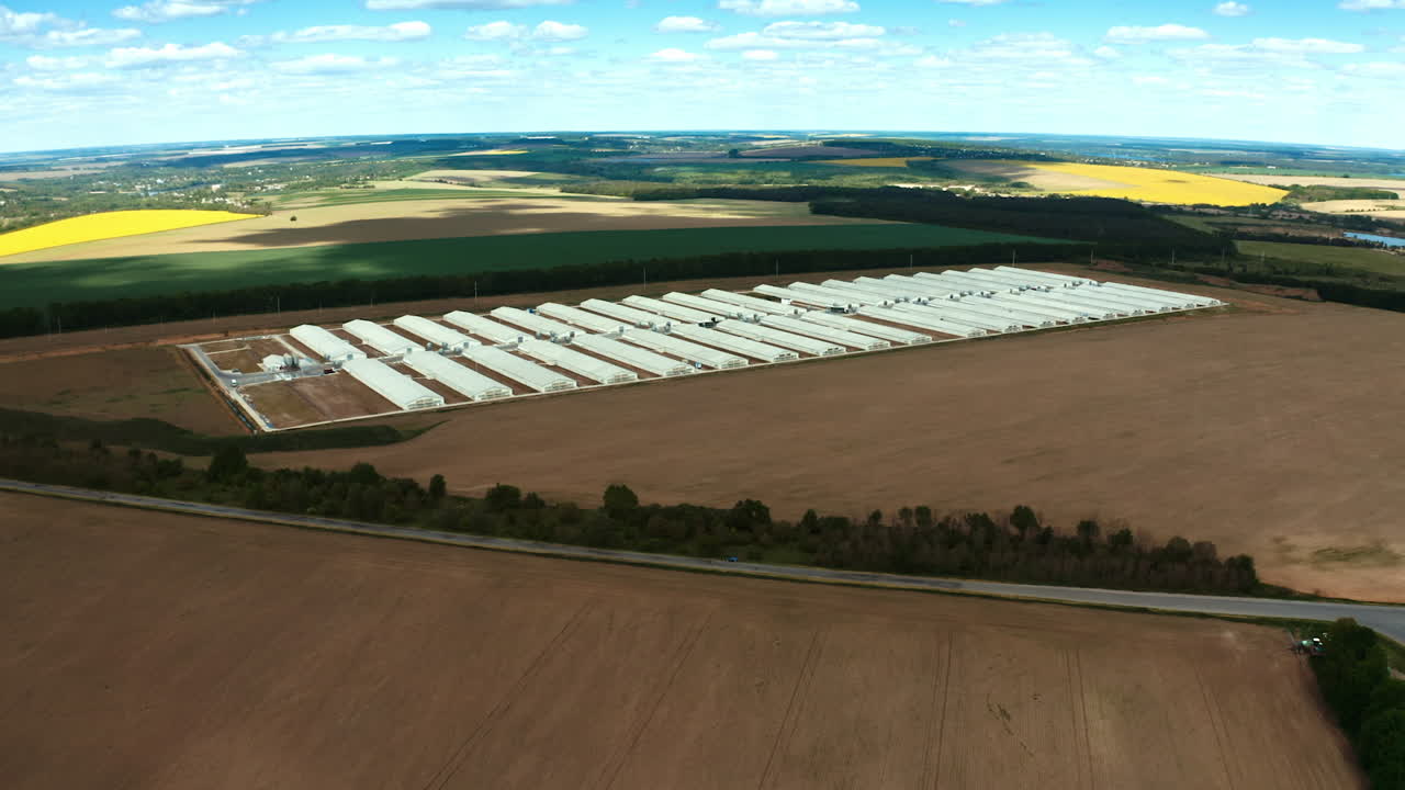 Exterior of large farm on an agricultural field. Modern factory with white buildings on nature background. Aerial view.