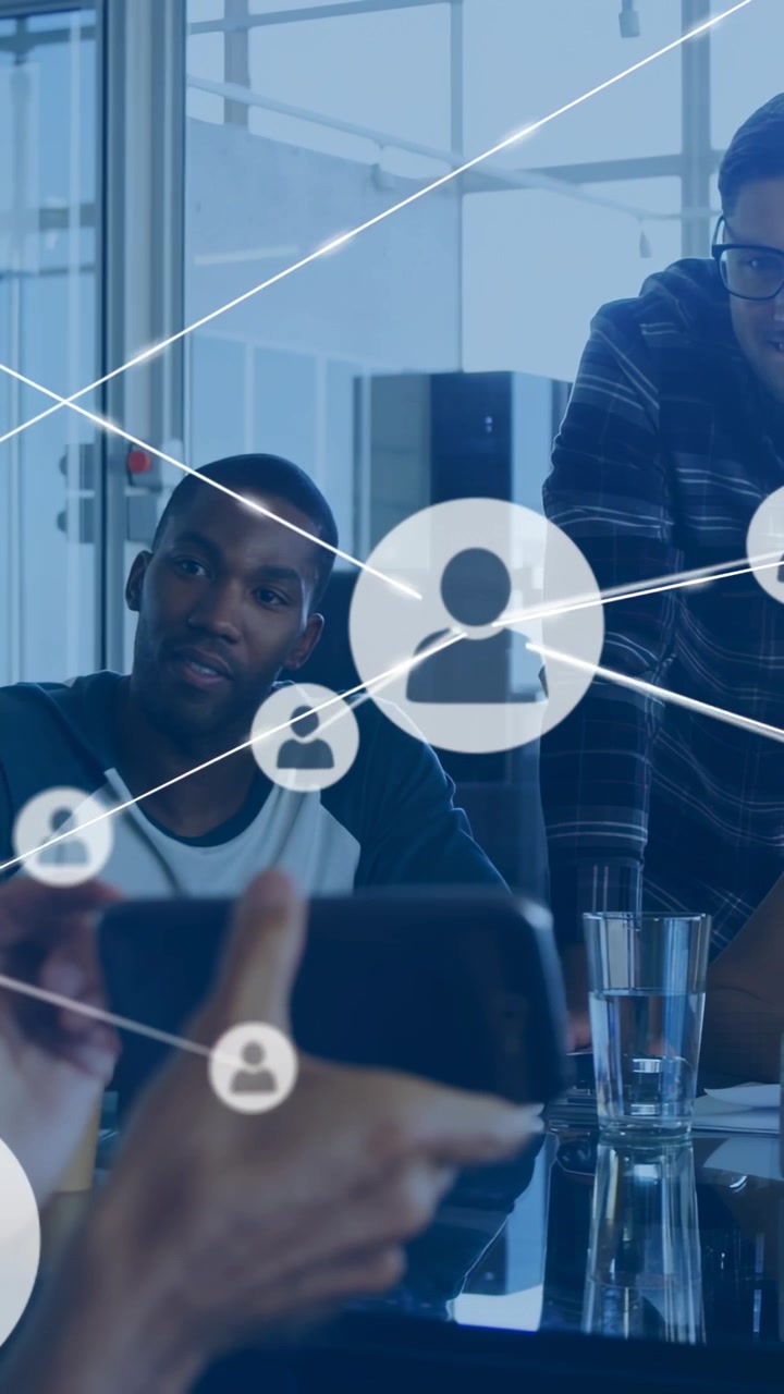 Mano che tiene il telefono e avvia un'interfaccia di rete, con un team che collabora in una riunione tecnologica mentre le icone si collegano.