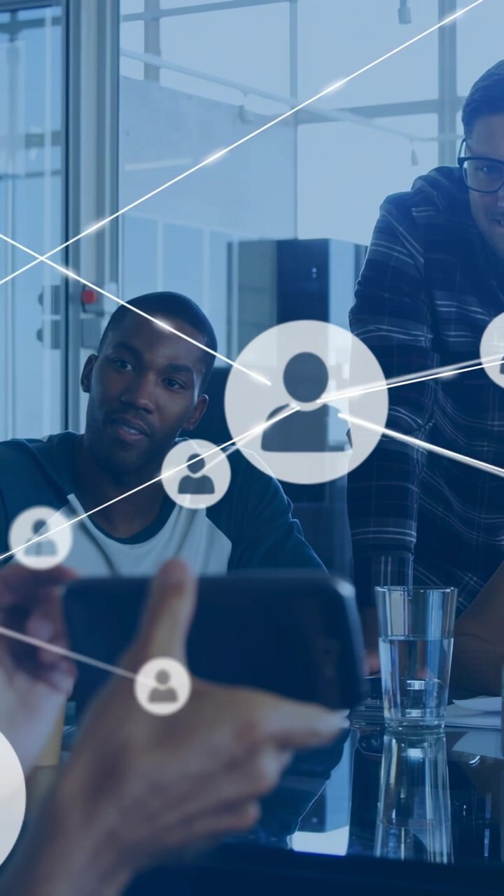 Mano che tiene il telefono e avvia un'interfaccia di rete, con un team che collabora in una riunione tecnologica mentre le icone si collegano.