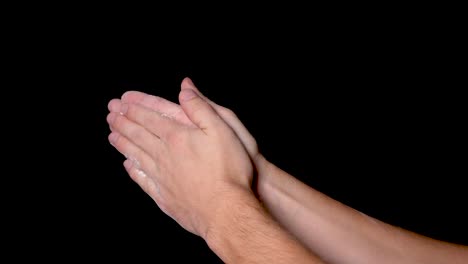 An-athlete-preparing-for-workout-by-chalking-and-clapping-his-hands-for-evenly-distributing-the-chalk-powder,-isolated-on-black-background