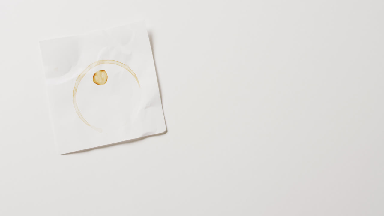 видео крупного плана куска бумаги с кофейной кружкой кольцо пятна на белом фоне с копировальным пространством