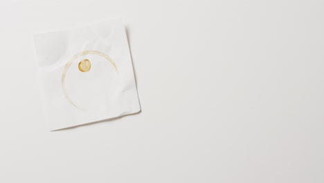 video de primer plano de un pedazo de papel con una taza de café mancha de anillo sobre fondo blanco con espacio de copia