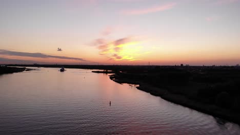 colorful sunset sky with silhouetted barge ship sailing across the river