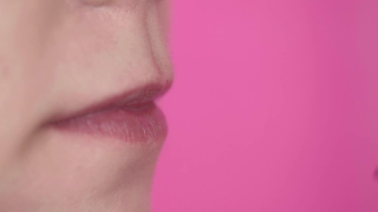 Primo piano di una donna che applica un lucidalabbra rosa vibrante