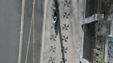 una acera decorada con dos patrones triangulares de columna y una motocicleta estacionada al lado del poste de la lámpara