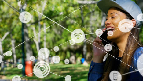 Animation-of-network-of-connections-with-icons-over-biracial-woman-talking-on-smartphone