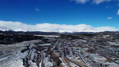 cloudy day flyover of fairplay, colorado on a winter day with blue skies